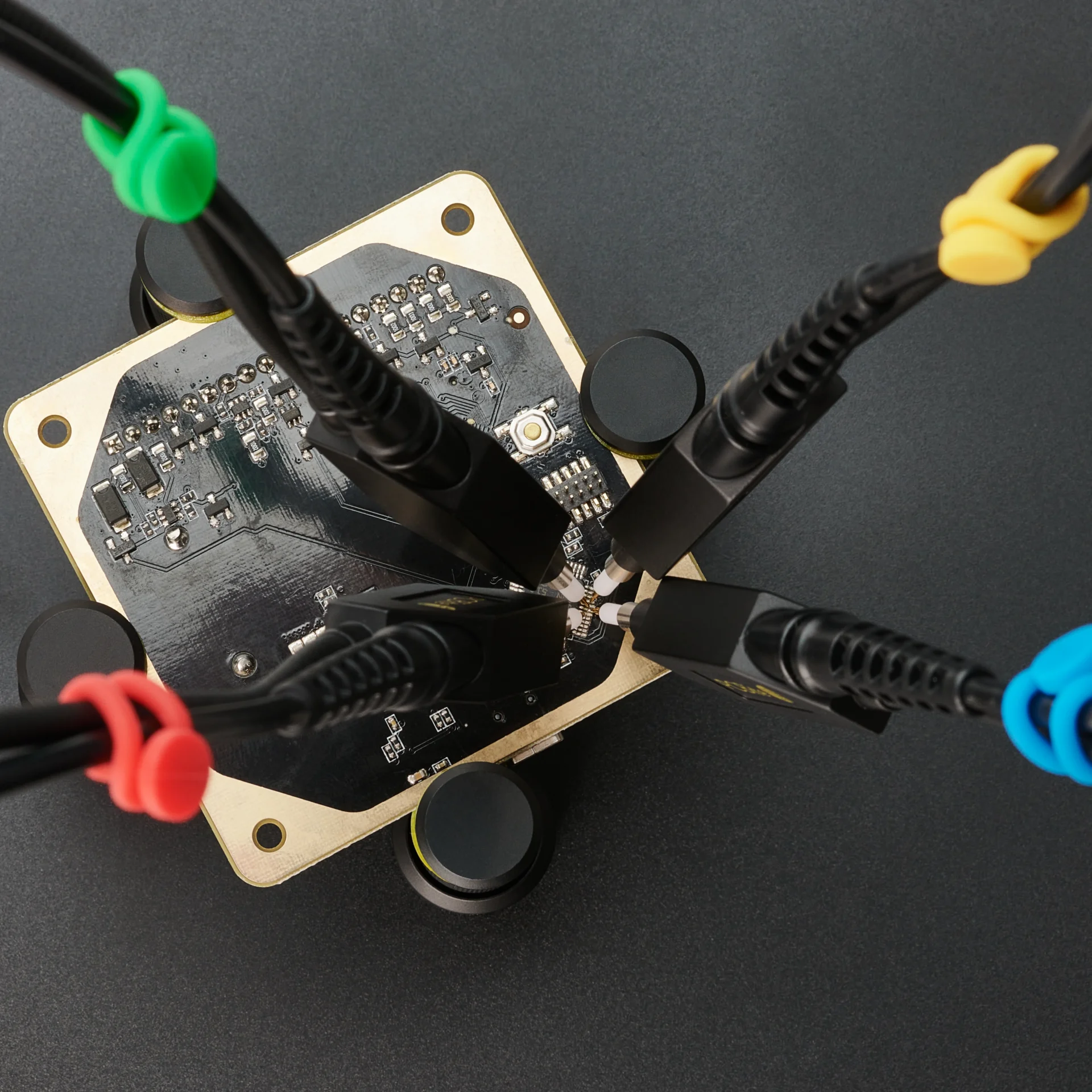 Four handsfree SQ100 100 MHz oscilloscope probes measuring on PCB with different color-coded cable holders (PCBITE-6013)
