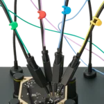 Four handsfree SQ10 probes with spring-loaded tips probing PCB signals with color-coded cable holders (PCBITE-6019)