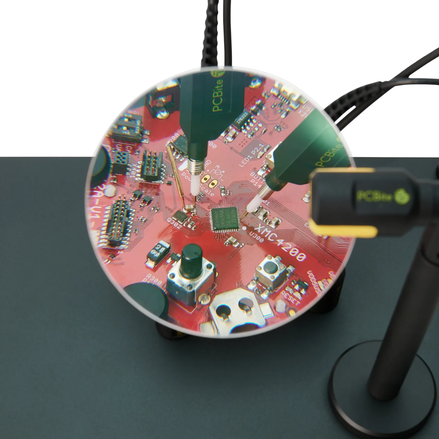 Two SQ500 500MHz oscilloscope probes measuring handsfree on PCB showing different grounding options through magnifier lens (PCBITE-6024)