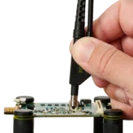 Hand placing a SQG60 6.0 GHz probe on PCB track for long and stable test (PCBITE-7012)