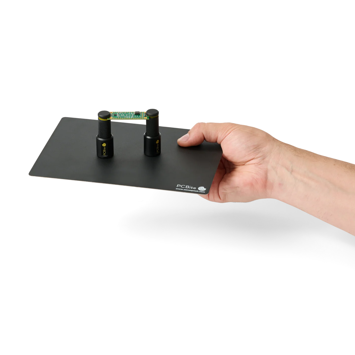 Hand handing over a setup with two spring-loaded PCB holders on a small insulated baseplate (PCBITE-7025)