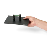 Hand handing over a setup with two spring-loaded PCB holders on a small insulated baseplate (PCBITE-7025)