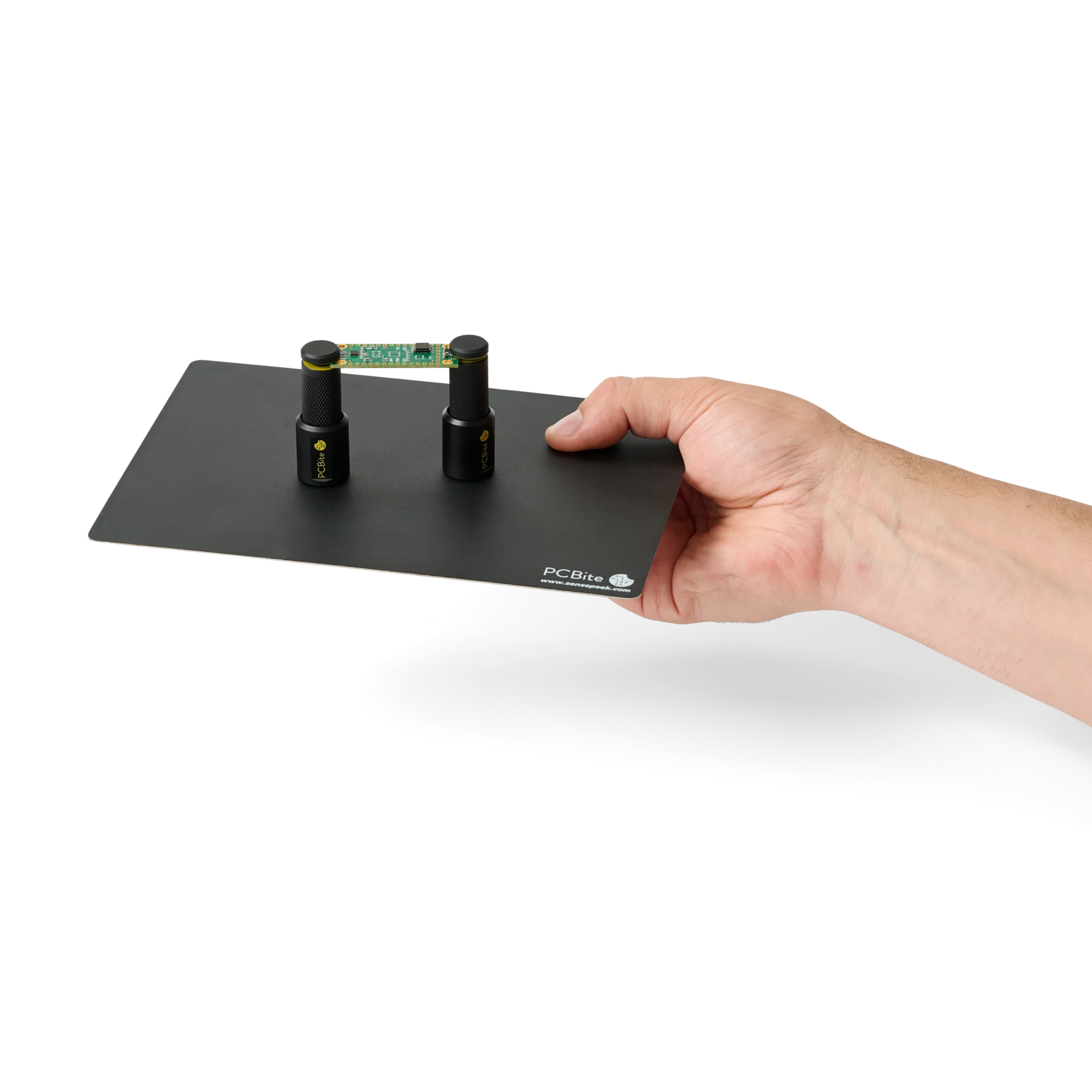 Hand handing over a setup with two spring-loaded PCB holders on a small insulated baseplate (PCBITE-7025)