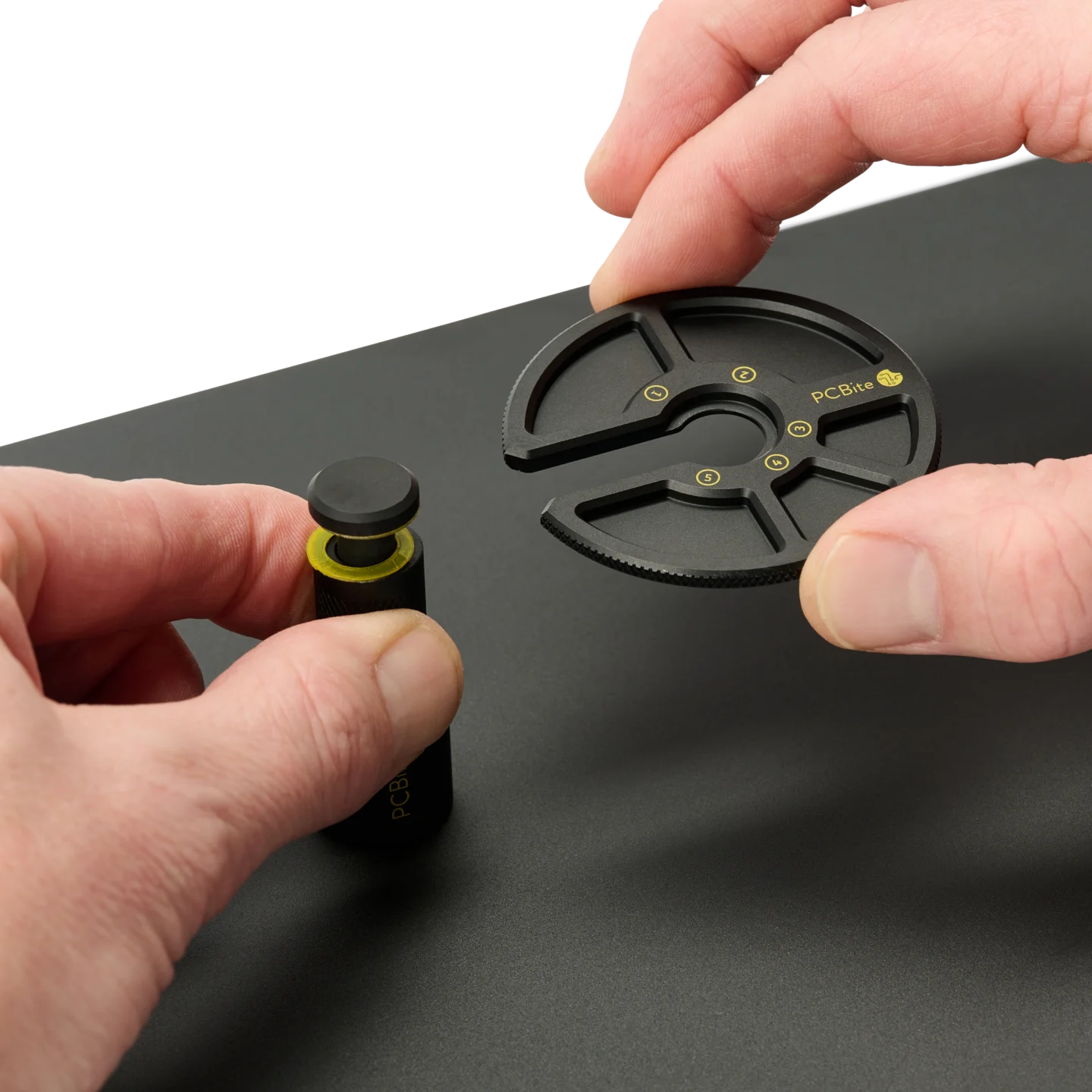 Hand opening a PCB holder and another holding the component tray (PCBITE-7029)