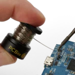 Closeup of hand holding the small wire stand when soldering on PCB (PCBITE-7030)