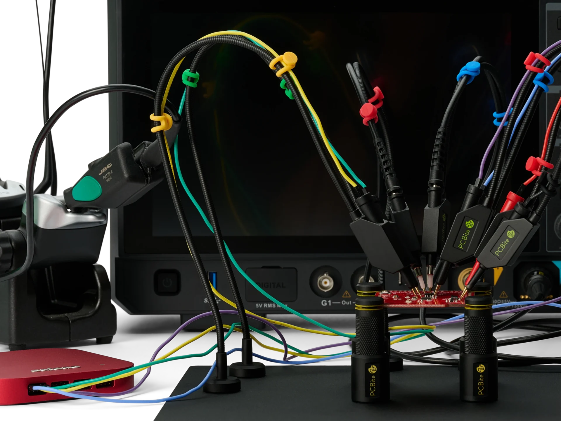 Handsfree probes with color-coded wires on a small PCB, feeding a logic analyzer and an oscilloscope while the code runs, with a JBC soldering station in the background.