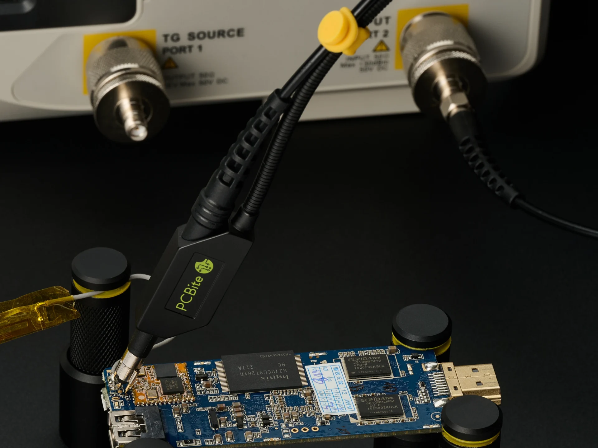 SQG probe placed handsfree near the antenna feed of a small PCB, its cable connected to the RF input of a spectrum analyzer.