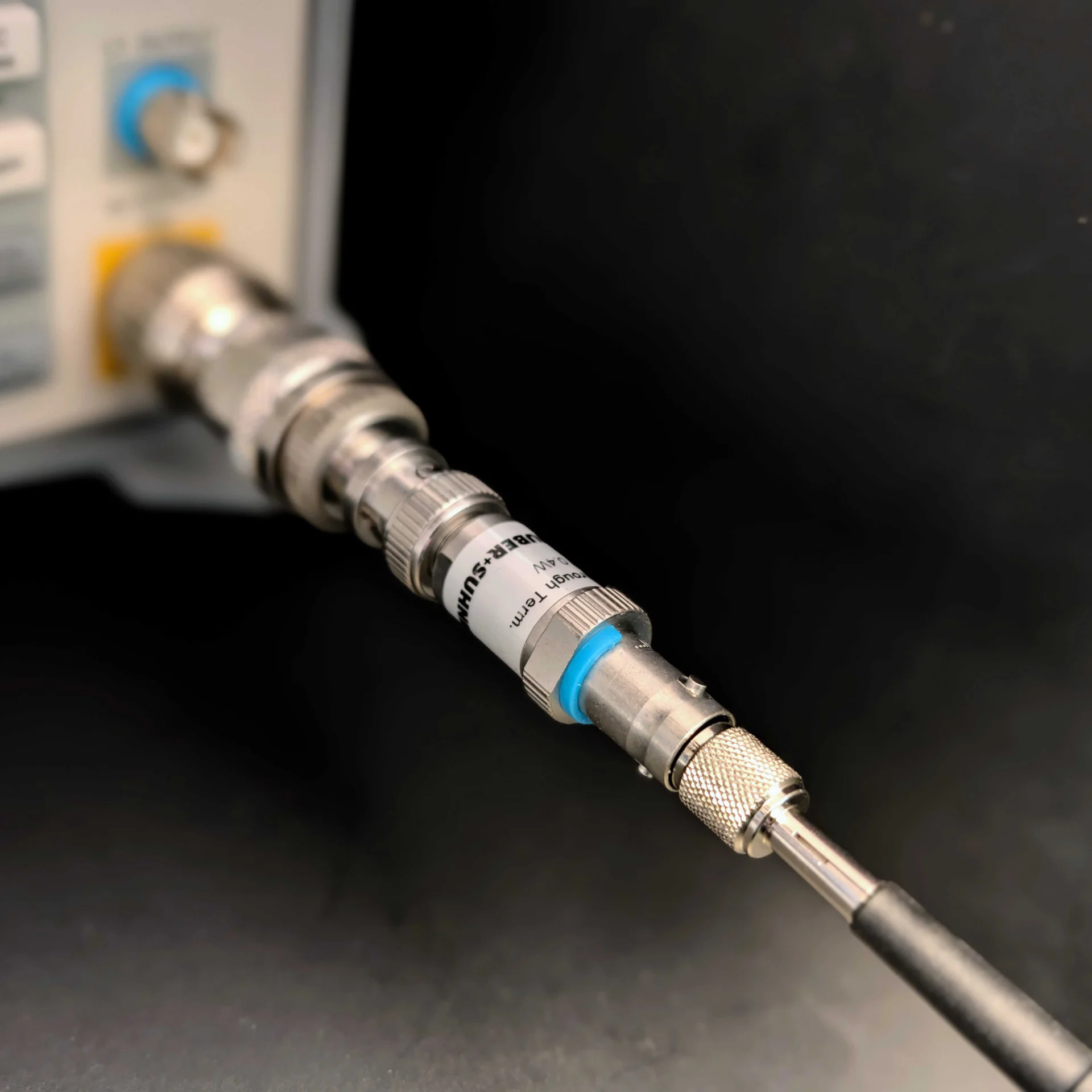 Oscilloscope probe connected to an instrument input through a PCBITE-7003 and a Huber+Suhner feedthrough termination as part of a frequency response measurement.